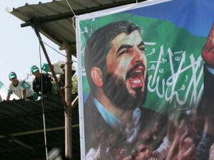 Palestinian supporters sit on the roof next to a poster of Hamas leader Khaled Meshaal. (Photo by Abid Katib/Getty Images)
