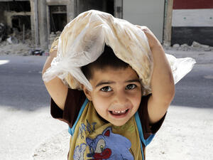 A Syrian boy carrying a bag of bread on his way home in Aleppo. (AFP/ Joseph Eid)