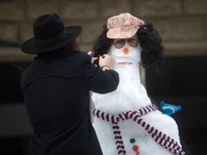 يهودي متشدد يصنع رجل ثلج في إسرائيل. (أ.ف.ب).  يهودي متشدد يصنع رجل ثلج في إسرائيل. (أ.ف.ب).