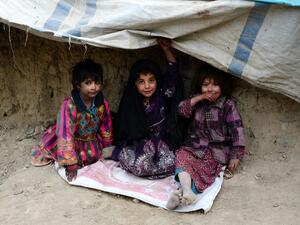 Internally displaced Afghan children sit outside their temporary home at a refugee camp in Kabul on December 16, 2016. (AFP/Noorullah Shirzada)