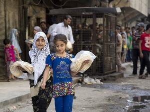 Two Syrian girls carry bags of bread in Aleppo. (AFP/Karam al-Masri)