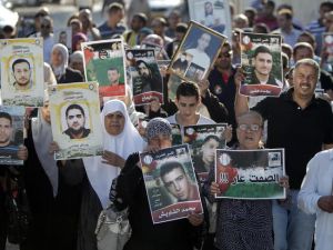 Palestinians hold posters with slogans and portraits of detainees during a demonstration on 10 June, 2014 outside the Red Cross building in Jerusalem in support of Palestinian prisoners who have been on hunger strike for six weeks. (AFP/File)