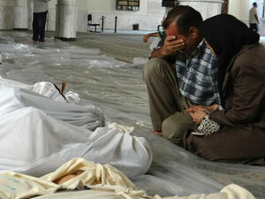A handout image released by the Syrian opposition's Shaam News Network shows a Syrian couple mourning in front of bodies wrapped in shrouds ahead of funerals following what Syrian rebels claim to be a toxic gas attack by pro-government forces in eastern Ghouta. (AFP/File)