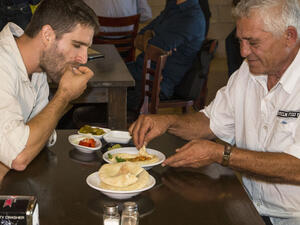 Two men share a plate of hummus at the Hummus bar. (AFP/File) 