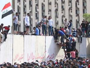 Iraqi protesters climb over a concrete wall surrounding the parliament after breaking into Baghdad's heavily fortified "Green Zone" on April 30, 2016. (AFP/Haidar Mohammed Ali)