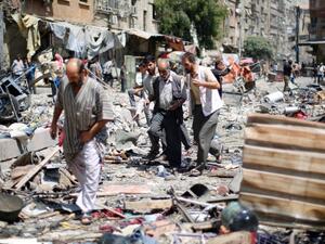 Syrians walk amid the rubble following air strikes by Syrian government forces on a marketplace, east of the capital Damascus. (AFP/File) 