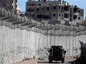 An Israeli police car patrols along a section of Israel’s Apartheid Wall that separates the West Bank city of al-Ram. (AFP/File)