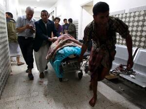 Yemenis transport a severely injured man on a gurney as he arrives at a hospital in Sanaa after being injured when two suicide bombers hit a Shiite mosque in quick succession, September 2, 2015. (AFP/Mohammed Huwais)