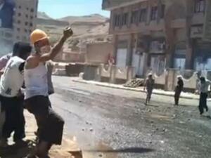 المتظاهر الذي يرتدي فانيلة بيضاء وخوذة برتقالية يرقص على صوت الرصاص!.