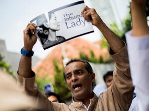 An Indonesian protester tears a picture of Aung San Suu Kyi during a rally in front of Myanmar embassy in Jakarta on September 2, 2017 (AFP)