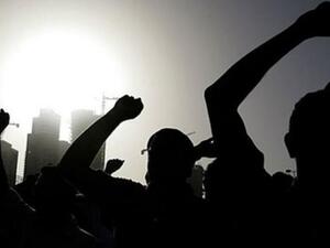 متظاهرون يرفعون قبضاتهم في الهواء في ساحة اللؤلؤة في وسط المنامة