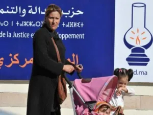 امراة تعبر مع اطفالها من امام لافتة انتخابية في الرباط