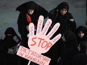 Bahraini women hold a placard reading 'Stop dictatorship in Bahrain' as they take part in an anti-government protest.(Image credit: AFP)