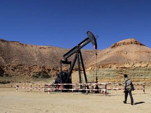 A Libyan security member walks past an oil drill on the Al-Ghani oil field near the city of Waddan on March 23, 2013. (AFP)