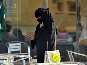 A Saudi woman looks at her mobile as she walks through a coffee shop. (AFP/File)