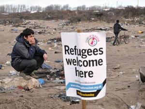 A migrant stands next to a banner in the port city of Calais, northern France, during a demonstration to support the migrants and refugees who live in the 'jungle'. (AFP/Francois Lo Presti)