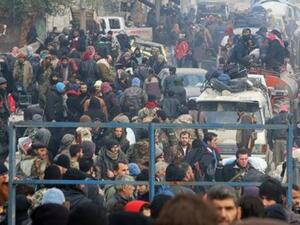 مقاتلو معارضة ومدنيون يتجمعون انتظارا لإجلائهم من منطقة تسيطر عليها المعارضة في شرق حلب يوم الجمعة

