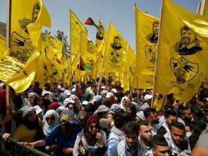 طلاب فلسطينيون مؤيدون لحركة فتح يرفعون اعلاما تحمل صورة الزعيم الراحل ياسر عرفات في تجمع انتخابي طلابي بجامعة بيرزيت قرب رام الله

