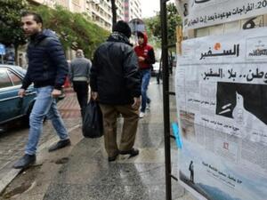 مارة بجانب نسخة من العدد الاخير من صحيفة "السفير" في منطقة الحمرا في بيروت

