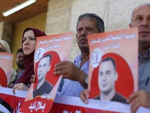 فلسطينيون يحملون صورا للاسير بلال كايد