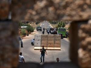 حافلة تنقل نازحين سوريين تقف على حاجز في بلدة بصرى في جنوب سوريا
