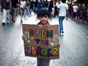 A child holds a placard reading "Open the border" during a demonstration in support to refugees and migrants in front of Athens municipality building, in Athens, on August 29, 2016. (AFP/Louisa Gouliamaki)