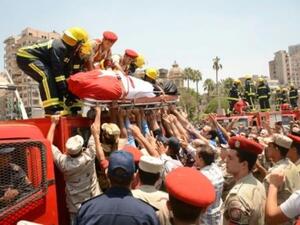 رجال شرطة وإطفاء ينزلون جثمان جندي قتل في شمال سيناء في اعتداء نفذه تنظيم الدولة الإسلامية، خلال تشييعه في المنصورة
