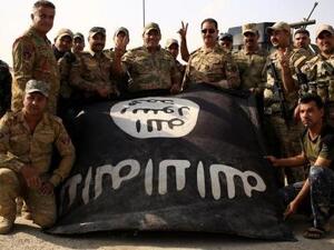 جنود عراقيون يحتفلون بالنصر على تنظيم الدولة الإسلامية في بلدة الشورة بجنوب الموصل ممسكين بعلم التنظيم مقلوبا يوم الأحد
