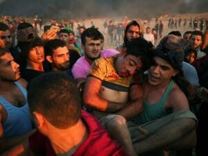 فلسطينيون يحملون فتى أصيب بجروح خلال مواجهات على السياج الفاصل بين إسرائيل وقطاع غزة
