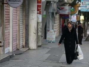 فلسطينية وسط محلات تجارية مغلقة بسبب الاضراب في غزة
