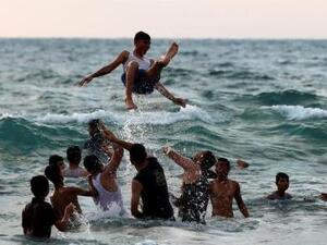 فلسطينيون يلهون في البحر على شاطئ قطاع غزة

