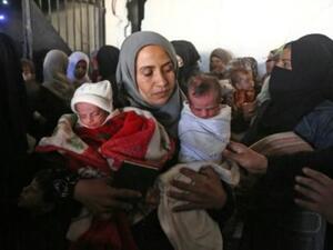 ام محمد تحمل رضيعيها اللذين يعانيان من سوء التغذية وهي تنتظر في مستوصف ببلدة النشابية في منطقةالغوطة الشرقية المحاصرة قرب دمشق

