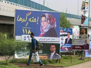 رجل يمر امام لافتة انتخابية في بغداد للمرشحة حنان نوري الربيعي.
