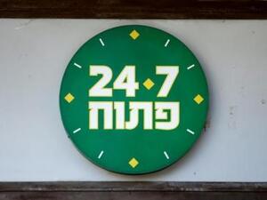 علامة في مدخل متجر للأطعمة بتل أبيب توضح استمرار العمل بالمتجر جميع ساعات اليوم وجميع أيام الأسبوع
