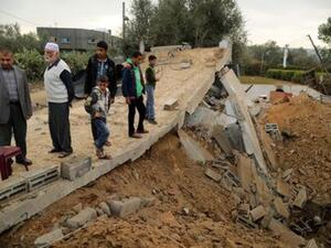 فلسطينيون يقفون على أنقاض مبنى دمرته غارة جوية إسرائيلية في خان يونس

