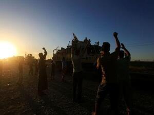 أشخاص يتجمعون على الطريق يرحبون بقوات الأمن العراقية الذين يواصلون التقدم على متن حافلات عسكرية في كركوك
