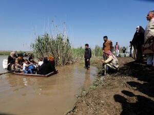 قارب يقل فارين من الموصل عبر نهر دجلة
