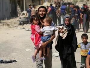 نازح عراقي فر من اشتباكات يحمل طفلين في غرب الموصل يوم السبت
