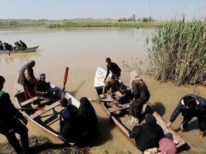 نازحون عراقيون يعبرون نهر دجلة باستخدام قارب بعد أن أغلقت فيضانات جسور الموصل

