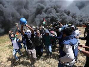 فلسطينيون يقومون بإجلاء الصحفي الفلسطيني ياسر مرتجى الذي أصيب بجروح مميتة أثناء تغطية الاشتباكات على الحدود بين إسرائيل
