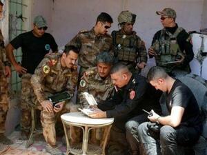 ضباط بالجيش العراقي يشاهدون شريطا مصورا نقلته طائرة بدون طيار على خط الجبهة في الموصل القديمة

