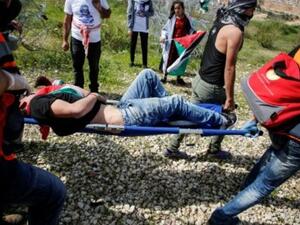 فلسطينيون ينقلون متظاهرا جريحا خلال مواجهات في قرية بلعين قرب الجدار الفاصل في الضفة الغربية المحتلة
