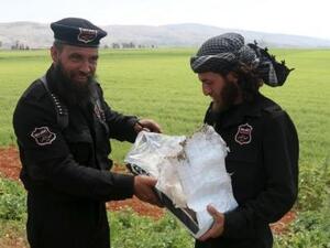 شرطيان من جبهة النصرة يعملان ضمن جماعة تسمى جيش الفتح. بحملان بقايا عبوة ناسفة عثر عليها على أطراف طريق يربط إدلب بمنطقة أرمناز في سوريا

