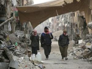 سوريون يسيرون وسط الدمار في مدينة الرقة
