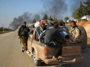 مقاتلون من المعارضة السورية على متن سيارة مع مدنيين فارين من ضاحية بغرب حلب 
