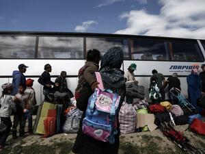 Refugees stand near a bus as they wait to be transferred to a hospitality center during a police operation at a refugee camp at the border between Greece and Macedonia, near the village of Idomeni on May 25, 2016. (AFP/Yannis Kolesidis) Refugees stand near a bus as they wait to be transferred to a hospitality center during a police operation at a refugee camp at the border between Greece and Macedonia, near the village of Idomeni on May 25, 2016. (AFP/Yannis Kolesidis)