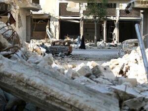 أشخاص يمشون بجوار مبنى مدمر في منطقة محاصرة تسيطر عليها المعارضة في حلب بسوريا
