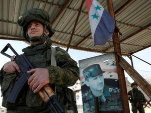 جندي روسي أمام صورة للرئيس السوري بشار الأسد في دمشق

