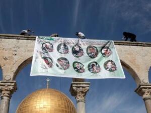 فلسطينيون يعلقون لافتة عليها صور شهداء تحتجز اسرائيل جثامينهم

