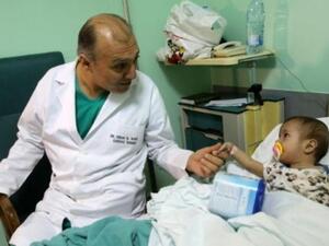 الدكتور عصام الراسي يمسك يد الطفلة السورية امينة حلو قبل اجراء جراحة لها في القلب في مستشفى حمود في صيدا

